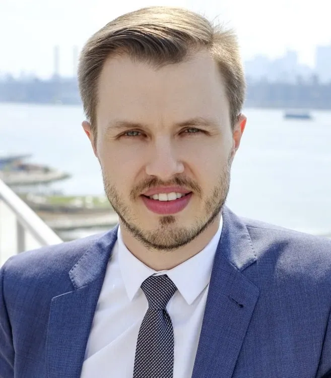 Dmitriy Ishimbayev, founder of Ishimbayev Law Firm, in a blue suit with the Manhattan skyline behind him